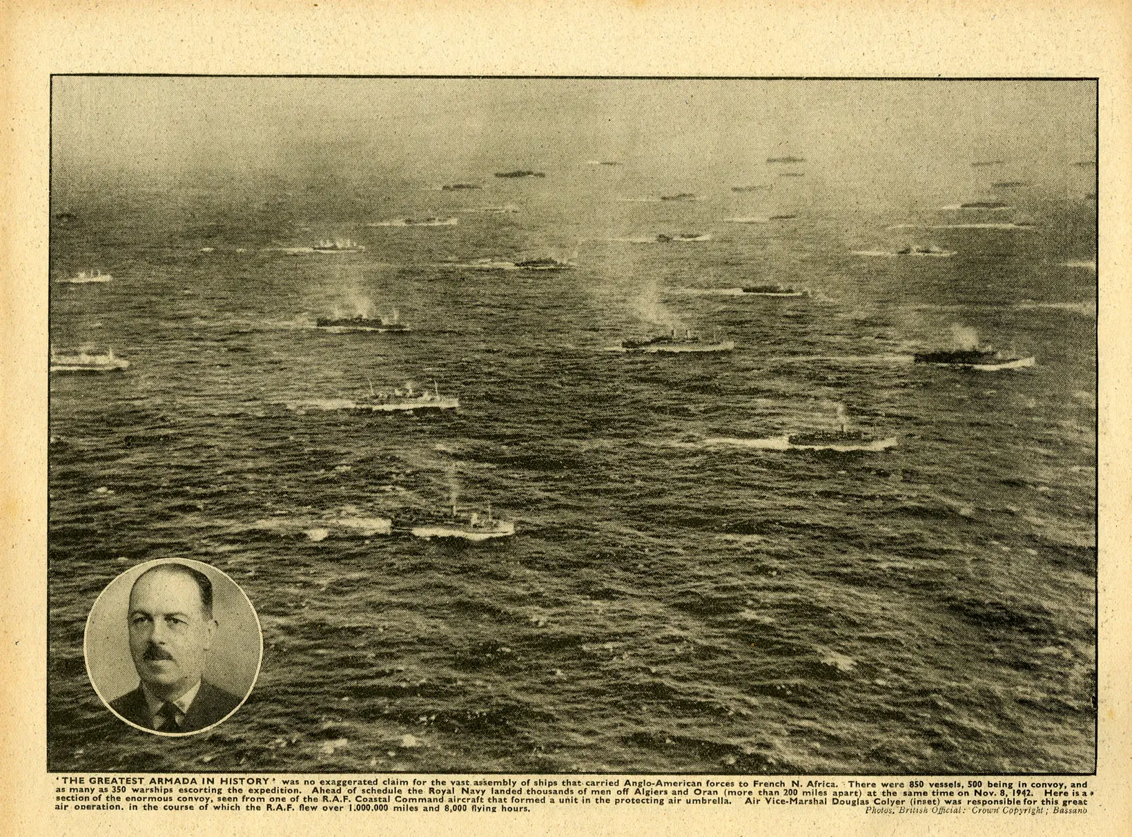 A page of The War Illustrated showing a full page aerial photograph of dozens of ships steaming in open waters. The ships are neatly organized into columns and packed closely together. There is a small portait of a man in the bottom left corner.